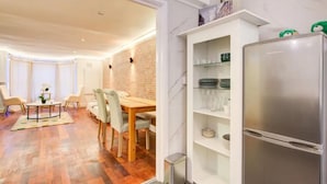 A modern kitchen with a built-in refrigerator, a dining area with a wooden table and chairs, and a brick accent wall. - Stunning London City Apartment Retreat (London)