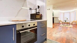 A kitchen with a microwave, oven, and a blue cabinet. There is a dining area with a table and chairs. - Stunning London City Apartment Retreat (London)