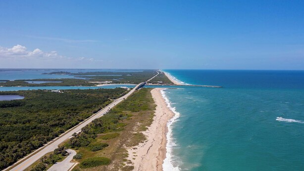 Vista aerea di una strada costiera con una spiaggia e un ponte.