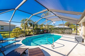 A covered outdoor swimming pool with lounge chairs and a shaded area.