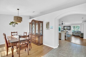 A dining area with a wooden table and chairs, a glass cabinet, and a hanging light fixture.