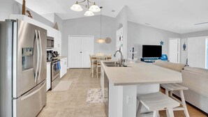 Una cucina moderna con isola centrale, elettrodomestici in acciaio inossidabile e zona pranzo con tavolo e sedie in legno.