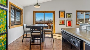 A modern kitchen with a dining area, large windows, and artwork on the walls. - Terrace Main | 5BR/3BA  | Spend Spring in Flagstaff! (Flagstaff)