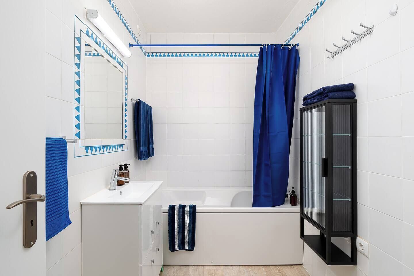 Ein Badezimmer mit Badewanne, Waschbecken, Spiegel und Duschvorhang.