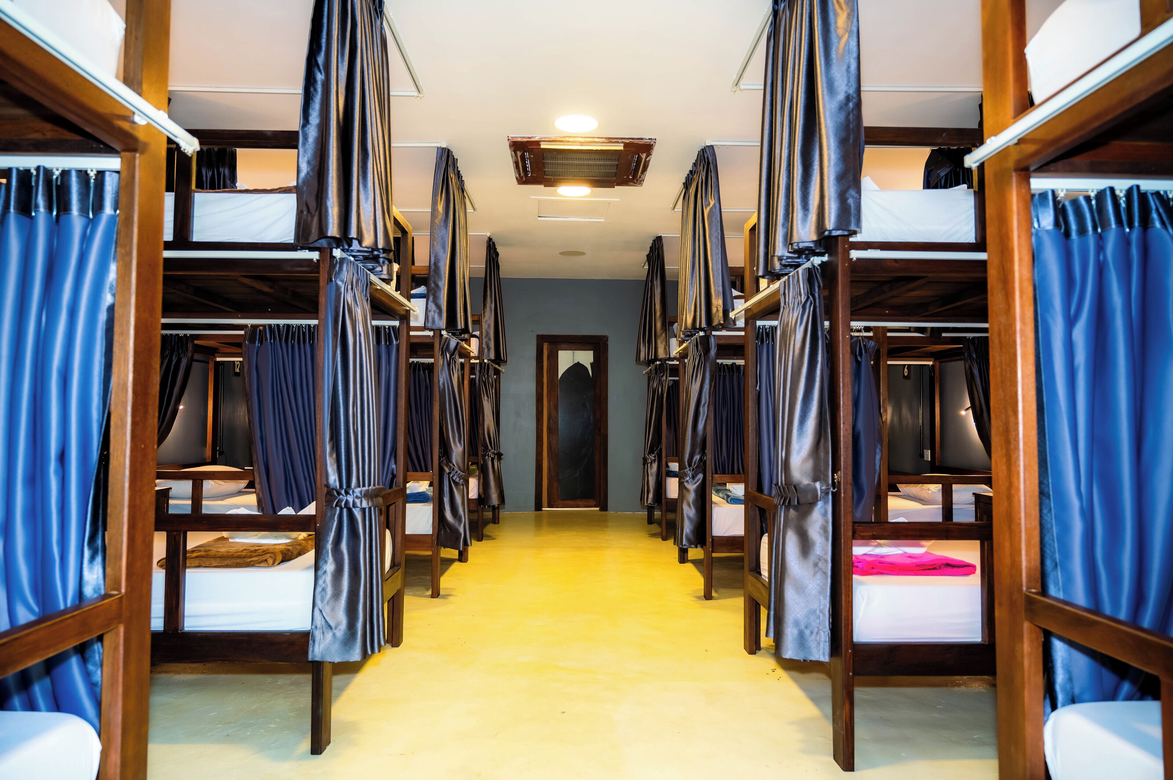 A corridor with bunk beds, wooden frames, and curtains.