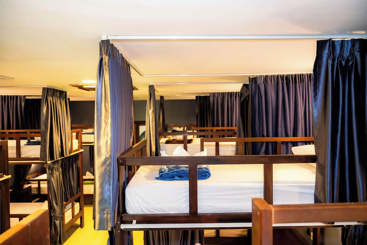 A room with bunk beds, wooden headboards, and curtains.