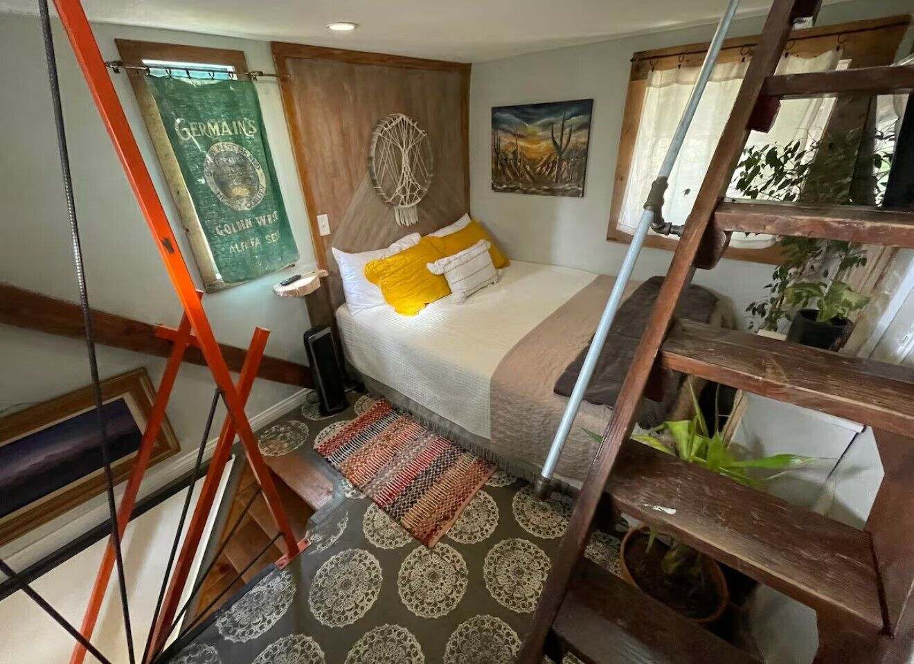 Un dormitorio con cama, cabecera de madera, una obra de arte en la pared, una escalera y una escalera de caracol.