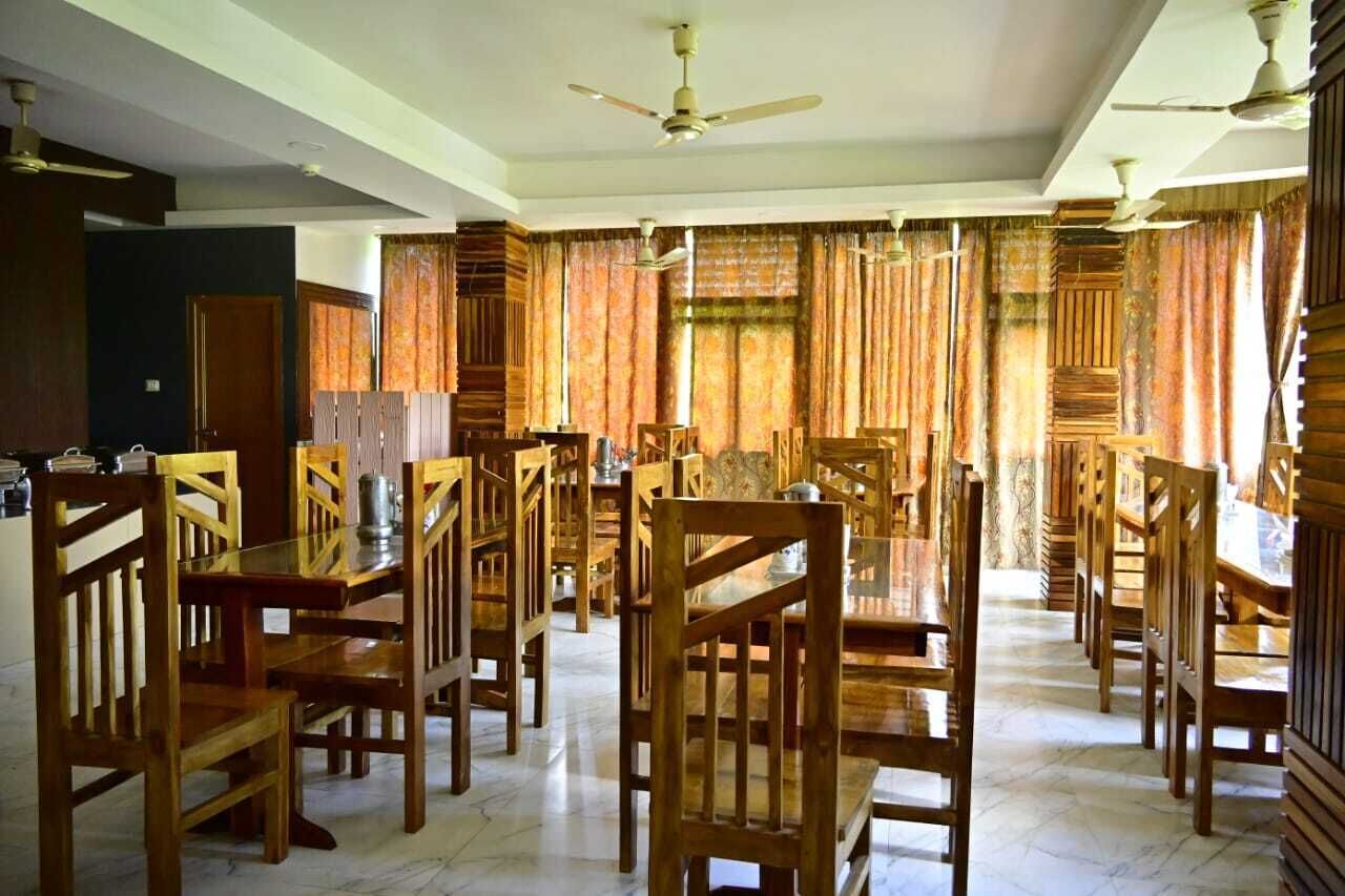 A dining area with wooden tables and chairs, ceiling fans, and curtains.