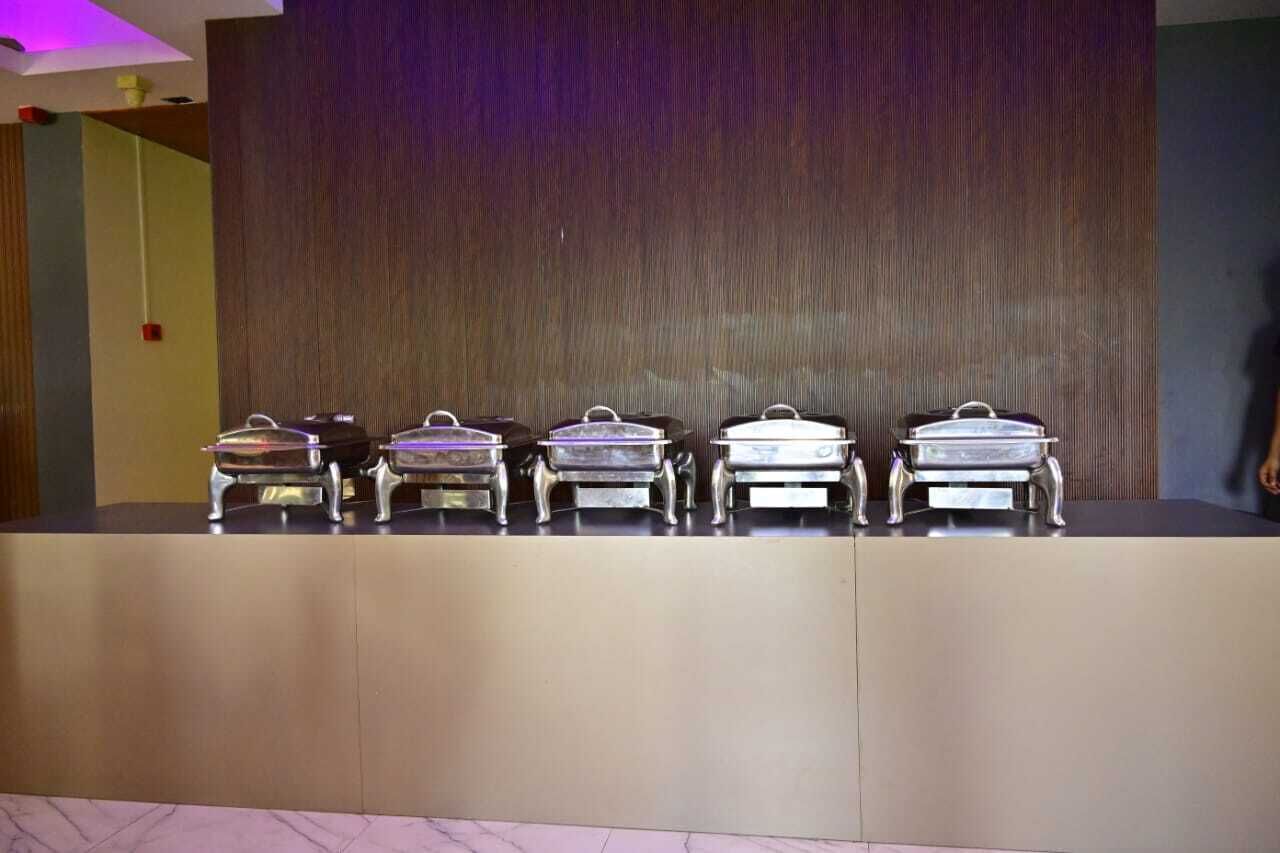 A buffet setup with five silver chafing dishes on a counter.