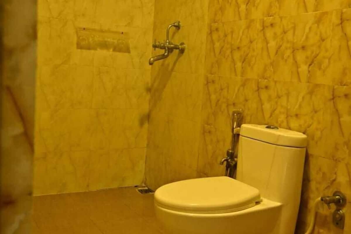 Un baño con inodoro, ducha y pared de mármol.