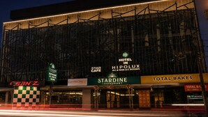 A hotel facade with multiple signs including 'Hotel in Hipolux AC & Non AC Rooms,' 'Star Cafe,' 'Stardine Restaurant,' 'San'z,' and 'Total Bakes.' - Hypolux Business Hotel (Palakkad)