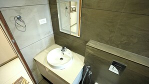 A bathroom with a white sink, a mirror, and a towel rack. - Hypolux Business Hotel (Palakkad)