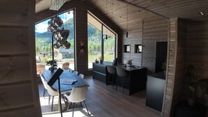 A modern kitchen with a large island, wooden walls, and a view of a mountainous landscape.