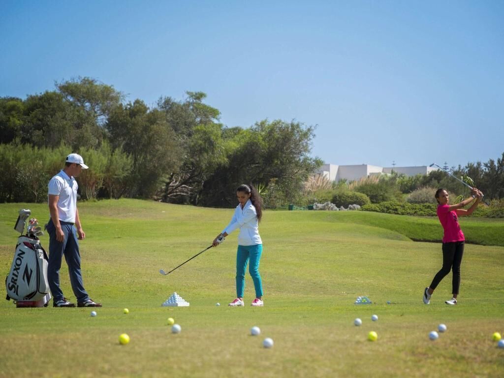 A golf course with players and a golf bag.