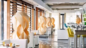 Un hall d’hôtel moderne au design épuré, avec un long comptoir d’accueil, des canapés blancs et un mur décoratif central.