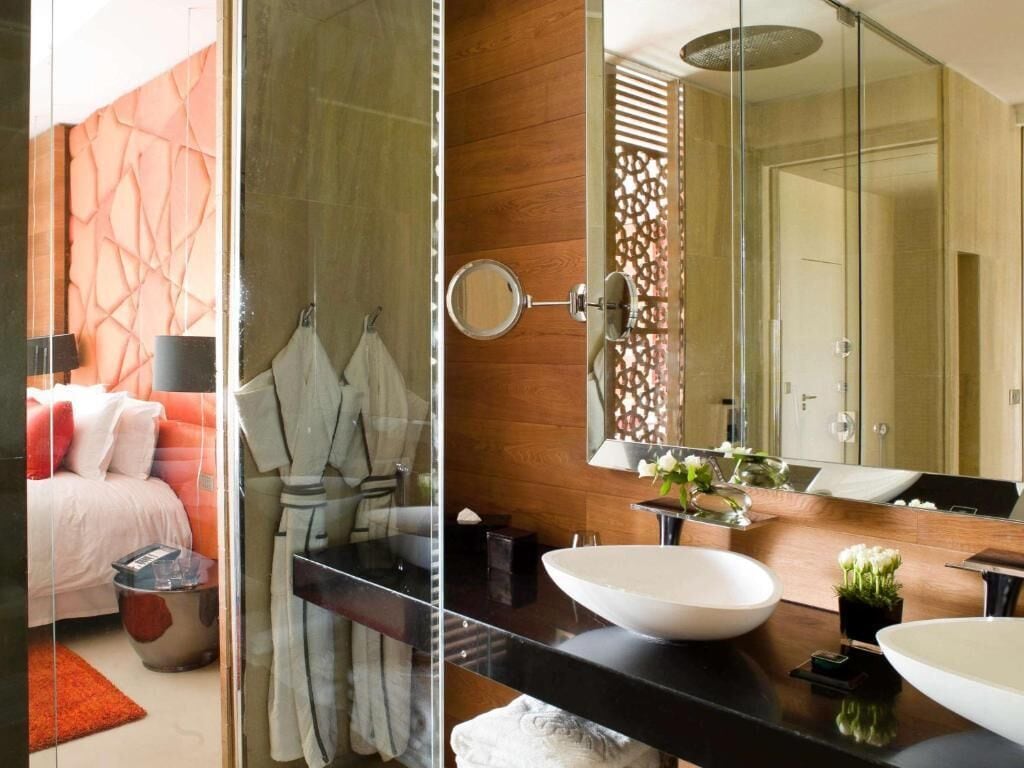 A modern bathroom with a large mirror, a white sink, and a glass shower enclosure.