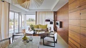 Une chambre d’hôtel moderne dotée d’une grande fenêtre, d’une table de salle à manger ronde et d’un coin salon confortable avec un canapé et des fauteuils.