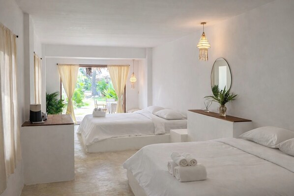 A hotel room with two beds, a desk, a mirror, and a view of the outdoors. - Riva Boutique Resort Koh Chang (Ko Chang)