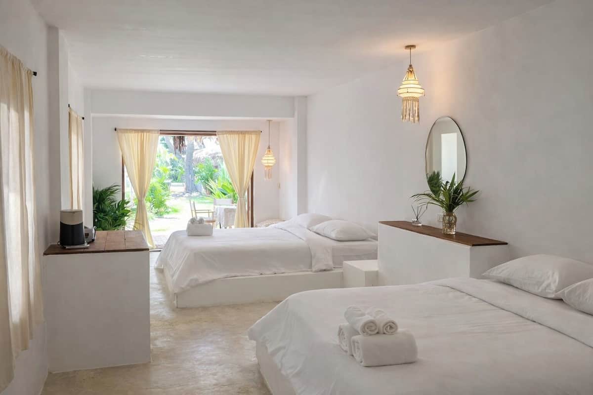 Habitación de hotel con dos camas, un escritorio, un espejo y vistas al exterior.
