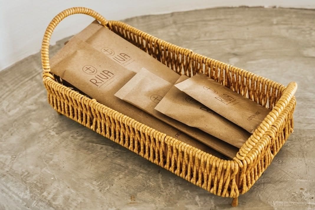 A wicker basket containing brown paper bags with a logo.