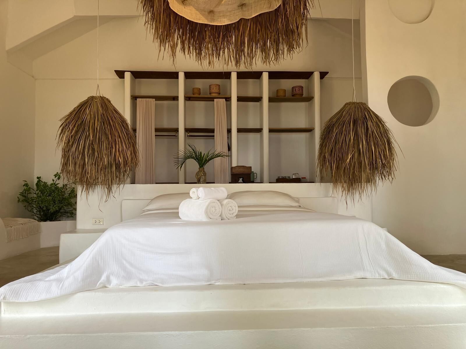 Ein Schlafzimmer mit einem Bett, einer Ablage mit Handtüchern und einem hängenden Korb.