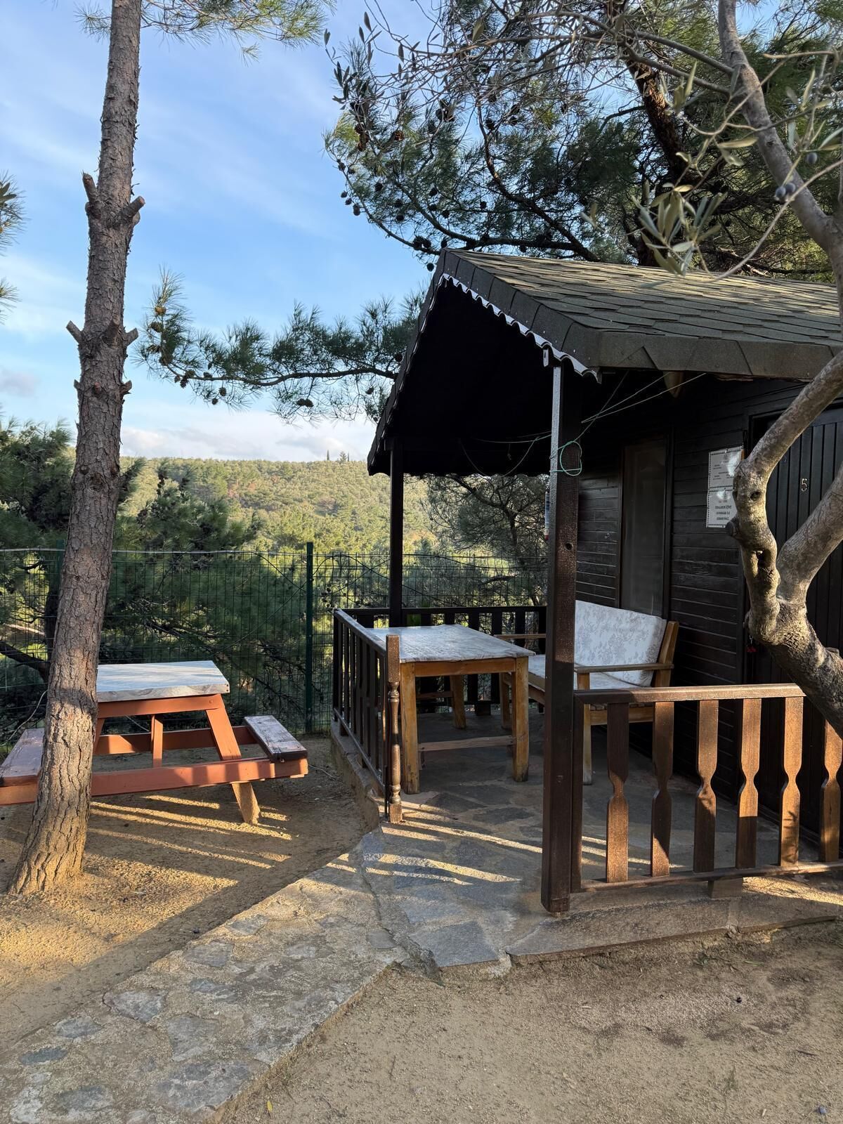 A rustic cabin with a wooden deck, picnic tables, and a covered seating area.