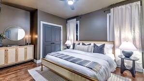 A bedroom with a bed, bedside tables, a ceiling fan, and a mirror.