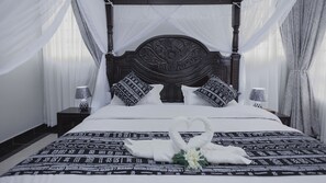 Ein Bett mit Baldachin, zwei Nachttische und ein dekoratives Kopfstück.
