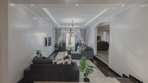 Ein modernes Wohnzimmer mit einer Couch, einem Fernseher und einem Essbereich, mit einer Küche im Hintergrund.