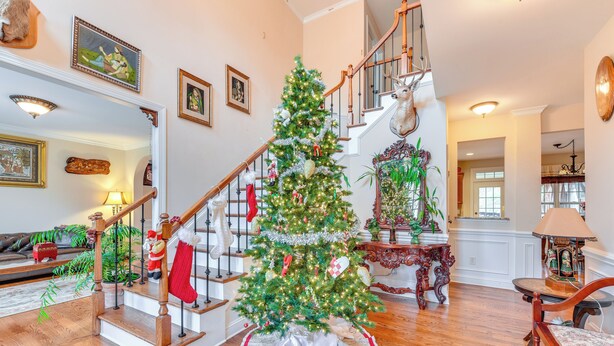 A spacious living room with a wooden staircase, a decorated Christmas tree, and a cozy fireplace. - 3 Mi to Carowinds: Retreat w/ On-site Fishing (Fort Mill)