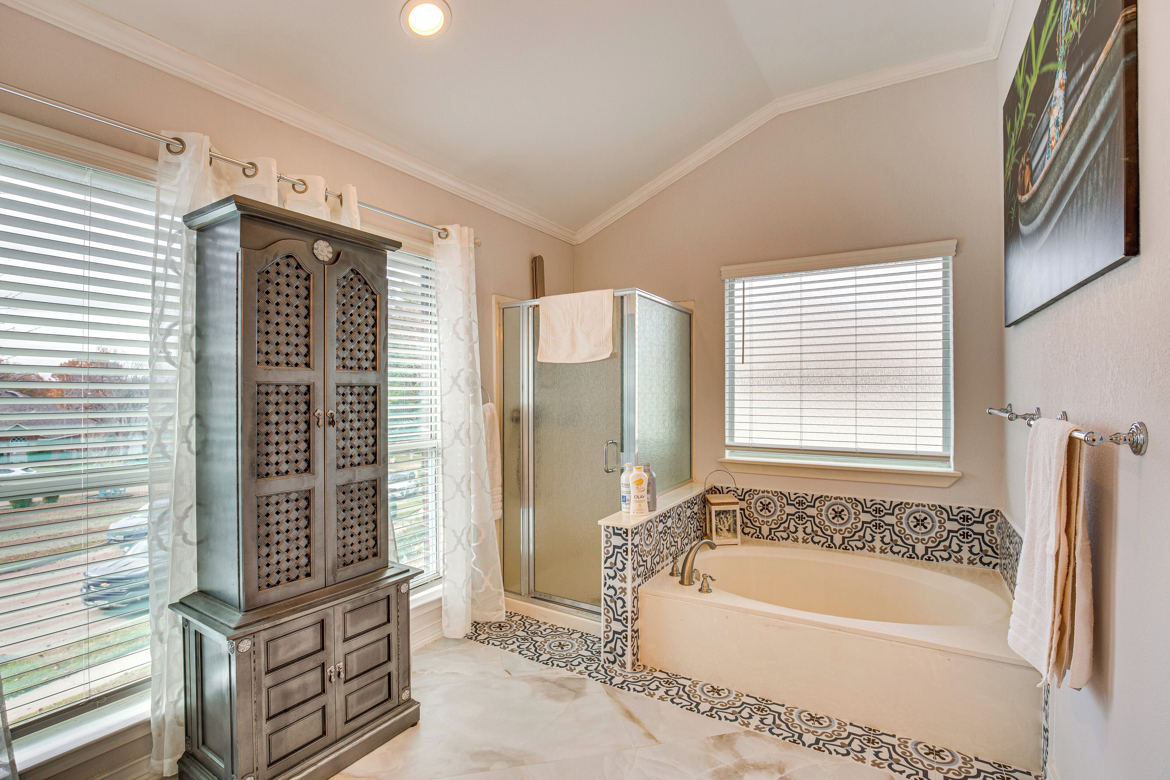 A bathroom with a walk-in shower, a freestanding bathtub, and a cabinet with decorative doors.