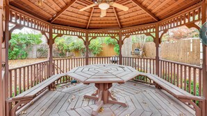 Un gazebo con tetto in legno e un tavolo al centro.