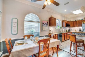 A dining area with a table set for four, wooden chairs, and a ceiling fan.