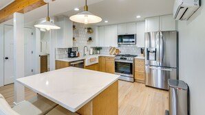 A modern kitchen with white cabinets, stainless steel appliances, and a marble island. - Pool & Hot Tub Access: Luxury Roy Oasis! (Roy)