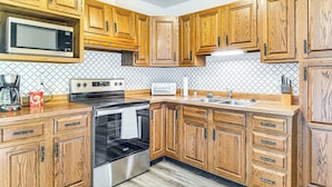 A kitchen with wooden cabinets, a microwave, a stove, and a sink. - 2 Mi to Downtown Logansport: Quiet Home w/ Grill (Logansport)