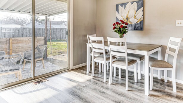 A dining area with a table and chairs, a sliding glass door leading to a patio, and a painting on the wall. - 2 Mi to Downtown Logansport: Quiet Home w/ Grill (Logansport)