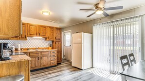 A kitchen with wooden cabinets, a white refrigerator, and a dining area with a table and chairs. - 2 Mi to Downtown Logansport: Quiet Home w/ Grill (Logansport)