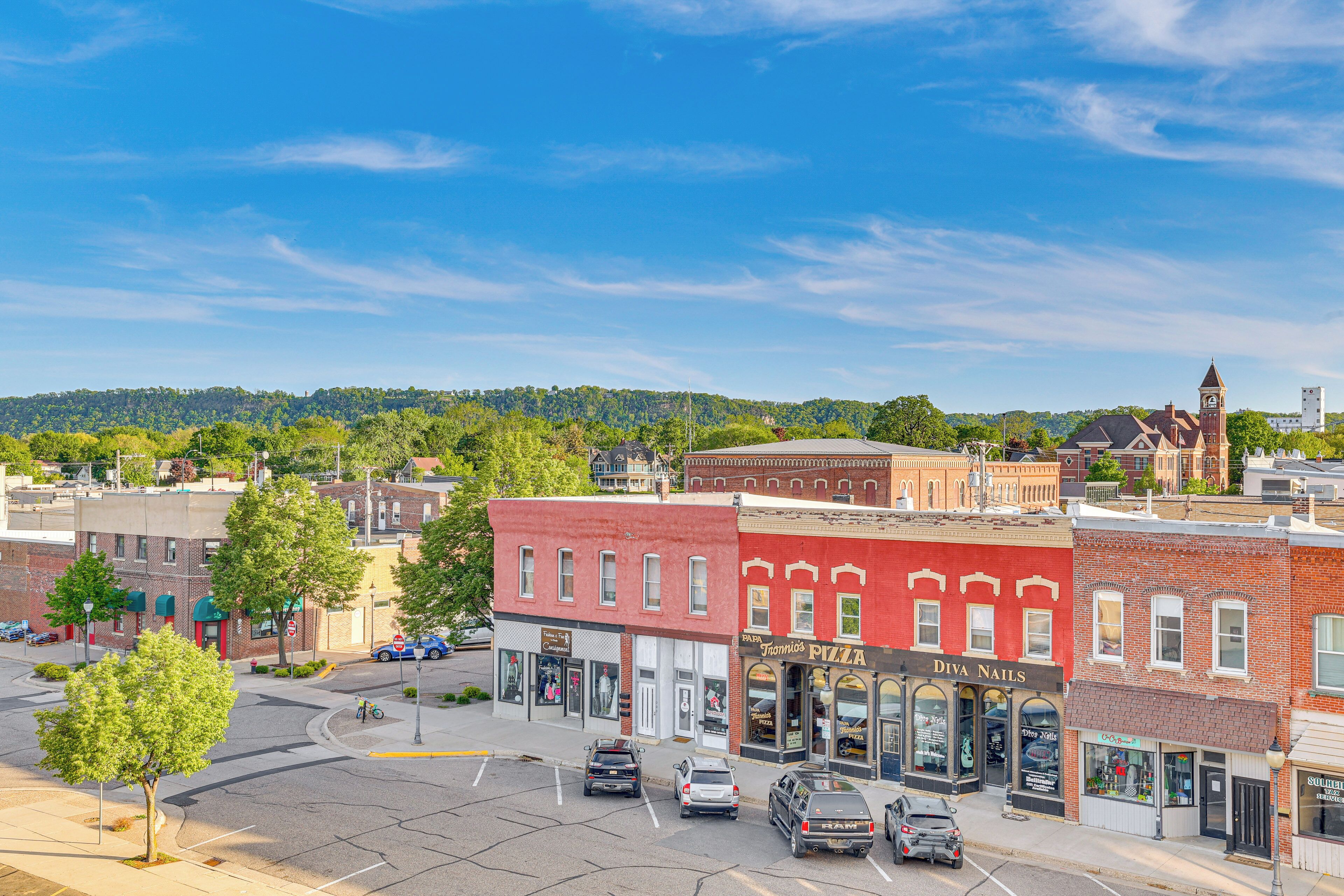 A downtown street with various shops, including a pizza place and a nail salon.