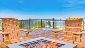 Une terrasse avec deux chaises en bois et un foyer.