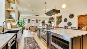 A modern kitchen with a large island, built-in appliances, and a dining area with a brick accent wall.
