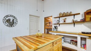 Een keuken met een houten kookeiland, witte kastjes en een welkomstbord aan de muur.