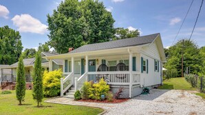 A single-story house with a porch, a gravel driveway, and a well-maintained lawn. - < 3 Mi to Dtwn: Modern Cottage in Greenville! (Greenville)