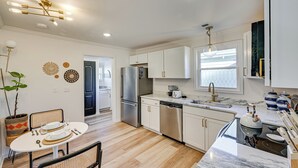 A modern kitchen with white cabinets, stainless steel appliances, and a marble countertop. - < 3 Mi to Dtwn: Modern Cottage in Greenville! (Greenville)