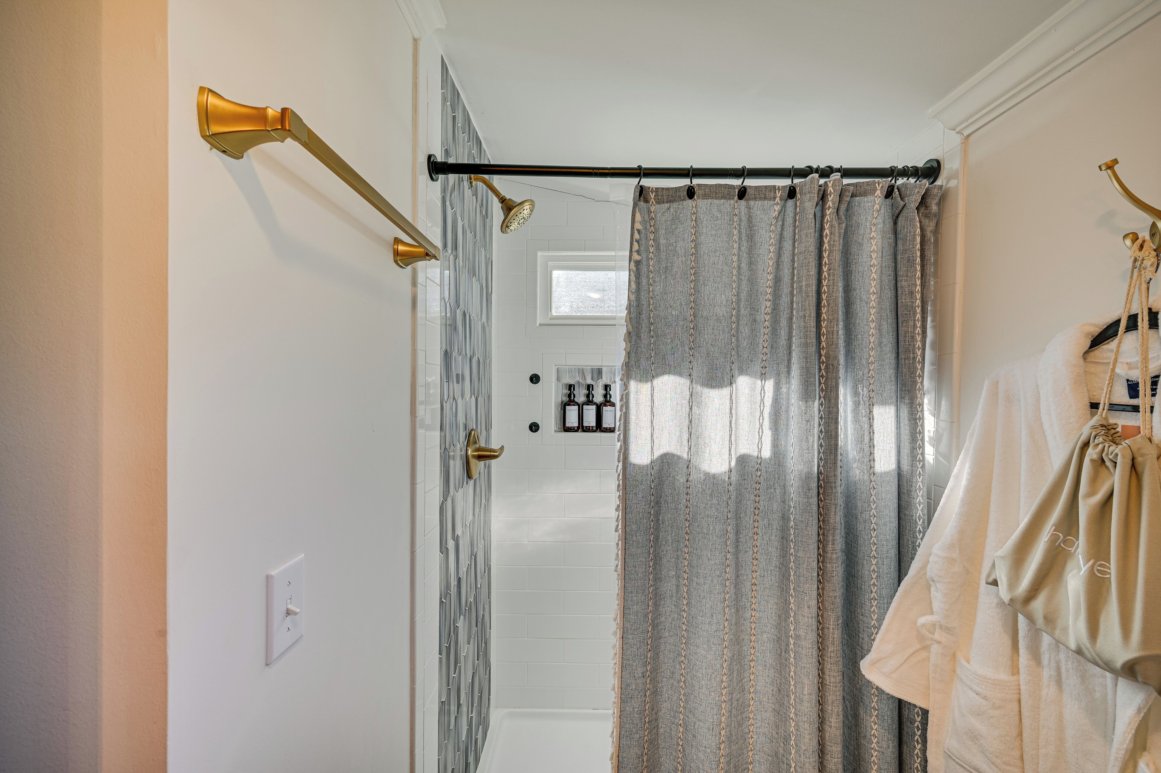 A bathroom with a shower, a towel rack, and a curtain.