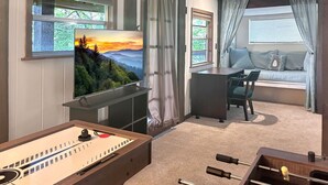 A cozy room with a foosball table, a TV mounted on the wall, a sofa, and a desk. - New! Bring Pets! Firepit*Fishing*Games*Sleeps 5! (Sevierville)