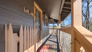 A wooden porch with a picket fence, a wooden door, and a tiled floor. - New! Bring Pets! Firepit*Fishing*Games*Sleeps 5! (Sevierville)