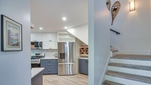 A modern kitchen with stainless steel appliances, a wooden staircase, and a framed picture on the wall. - Mtn Escape w/ Hot Tub, By Trails in Grand Lake! (Grand Lake)