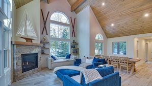A spacious living area with a stone fireplace, a large window with a sailboat decoration, and a cozy seating arrangement. - Mtn Escape w/ Hot Tub, By Trails in Grand Lake! (Grand Lake)