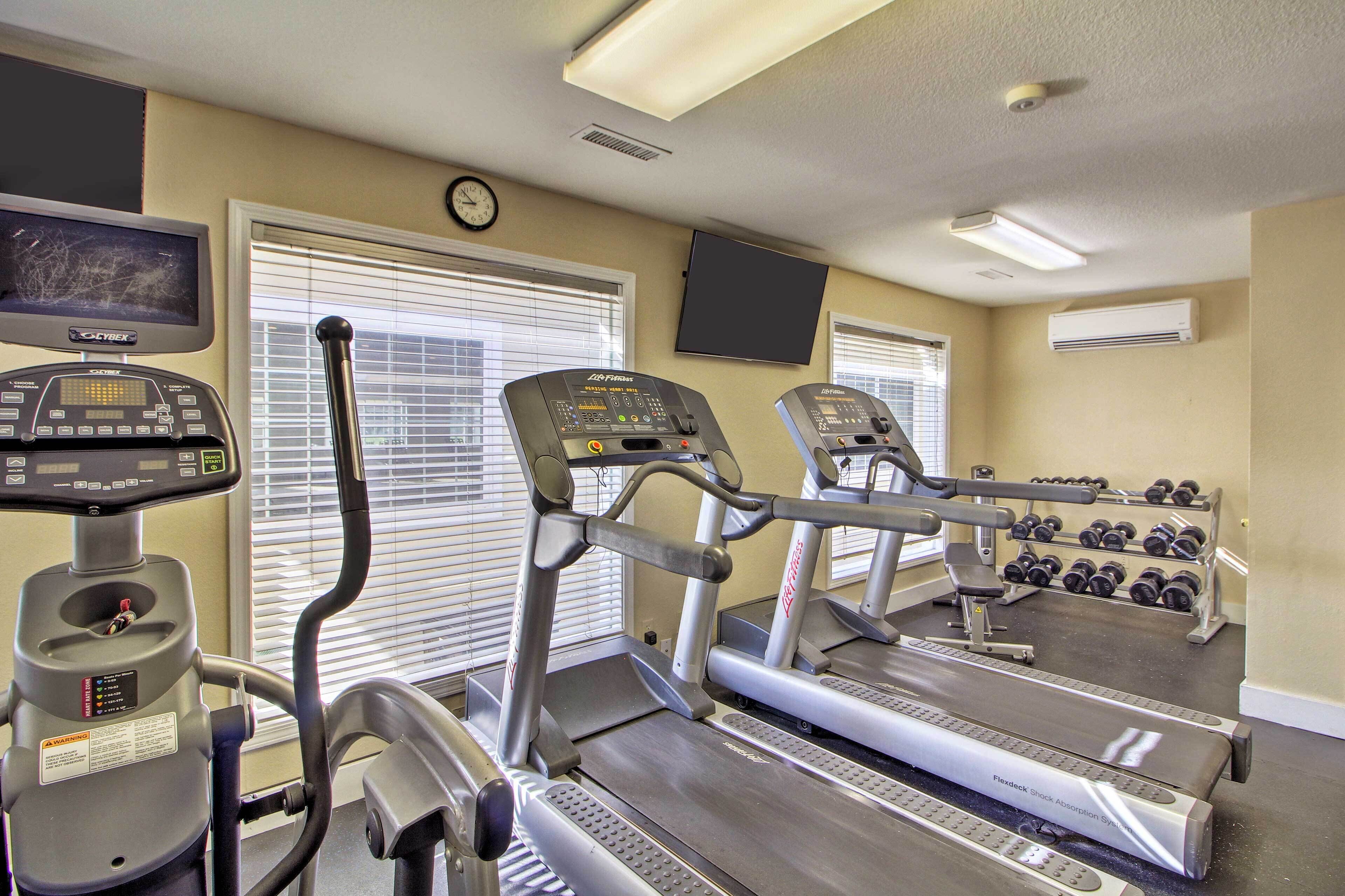 A gym with treadmills, a stationary bike, and a TV screen.