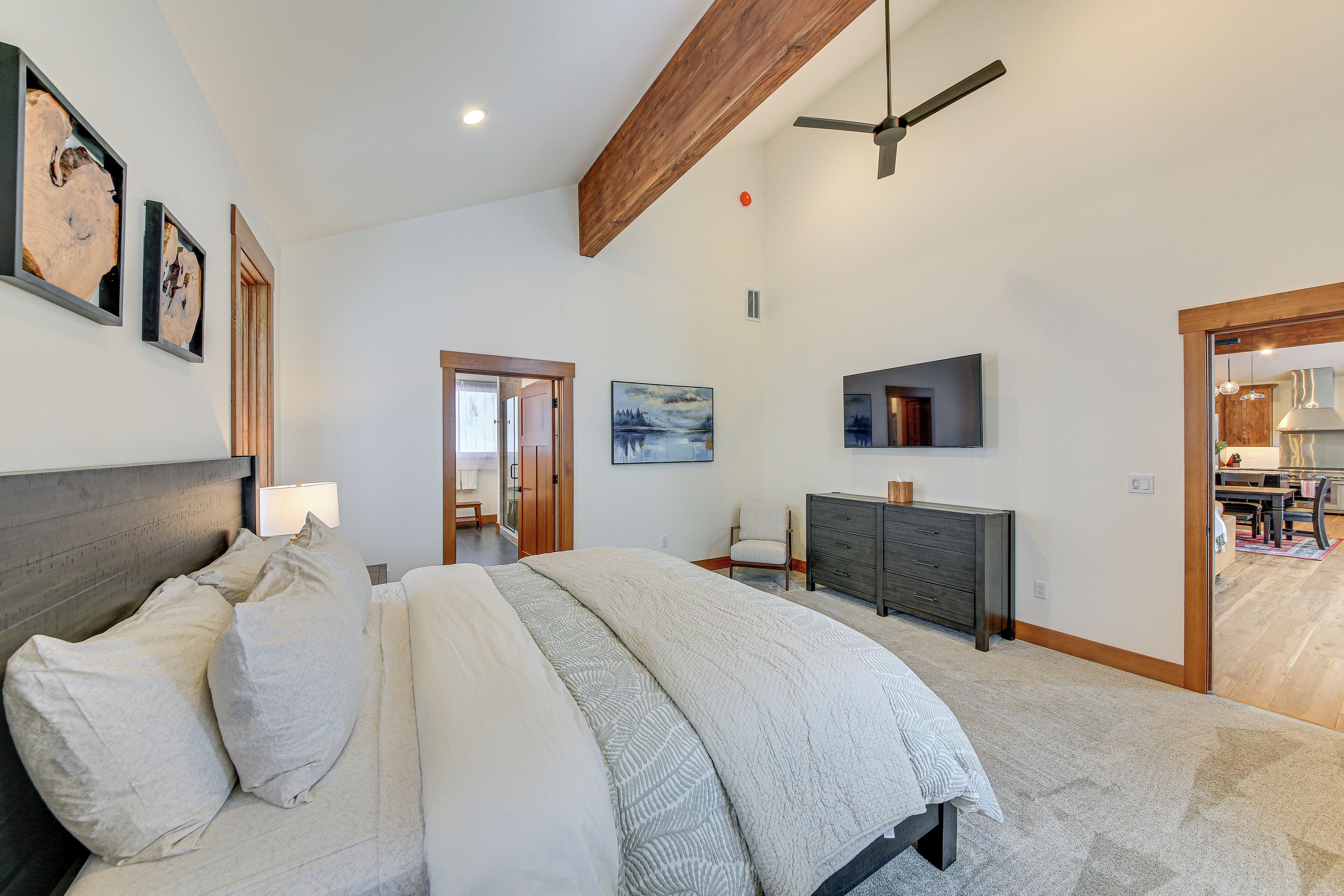 A bedroom with a large bed, a dresser, a TV, and a ceiling fan.